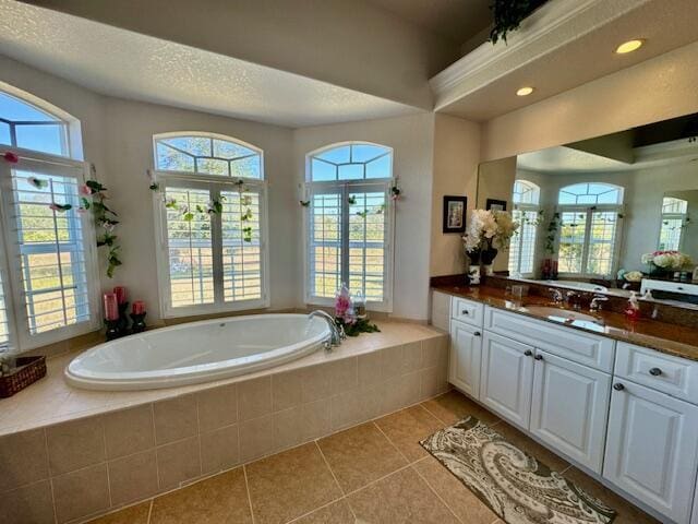 bathroom with tile patterned floors, vanity, plenty of natural light, and tiled tub