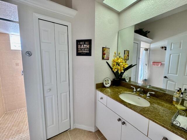 bathroom with tile patterned flooring, vanity, and walk in shower