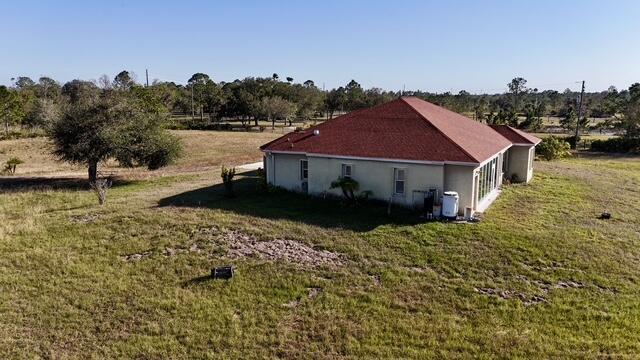 view of property exterior with a rural view and a lawn