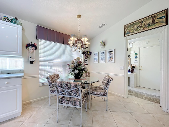 tiled dining room featuring a chandelier and vaulted ceiling