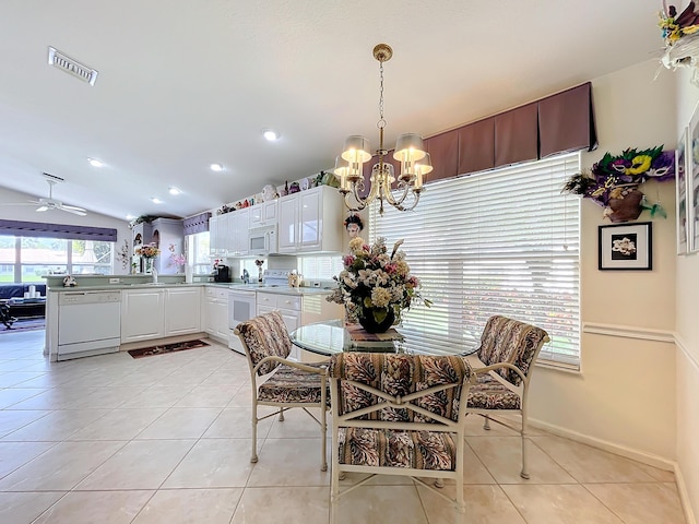 tiled dining space featuring ceiling fan with notable chandelier and lofted ceiling