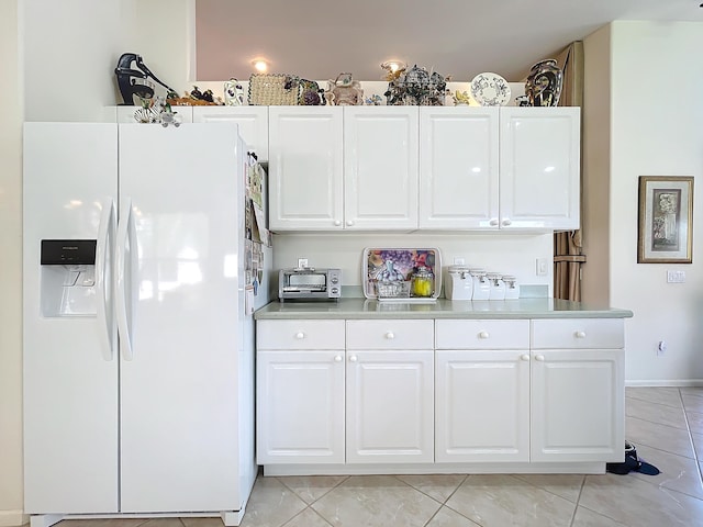 kitchen featuring white cabinetry, light tile patterned floors, and white refrigerator with ice dispenser