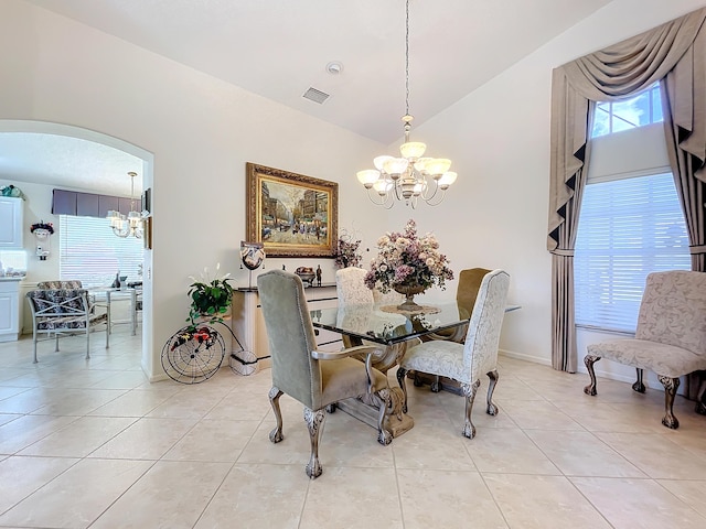 tiled dining area with vaulted ceiling and an inviting chandelier