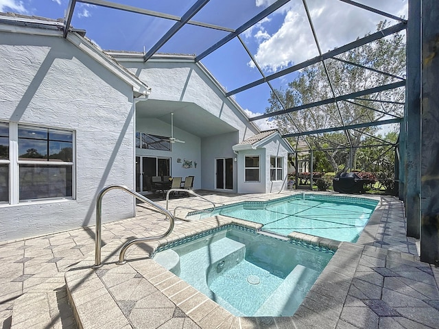 view of swimming pool with glass enclosure, ceiling fan, an in ground hot tub, and a patio