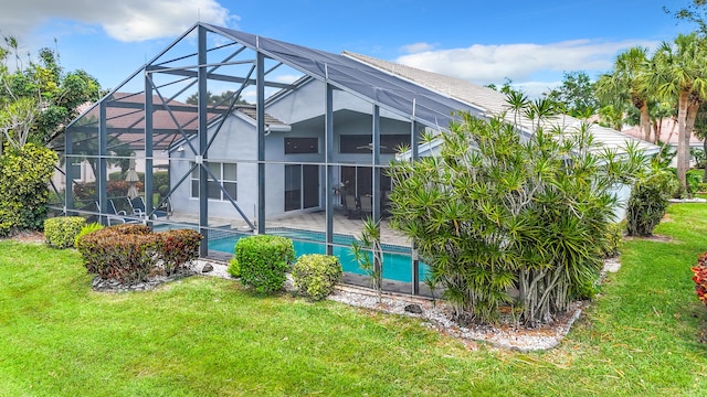 rear view of property with glass enclosure and a lawn