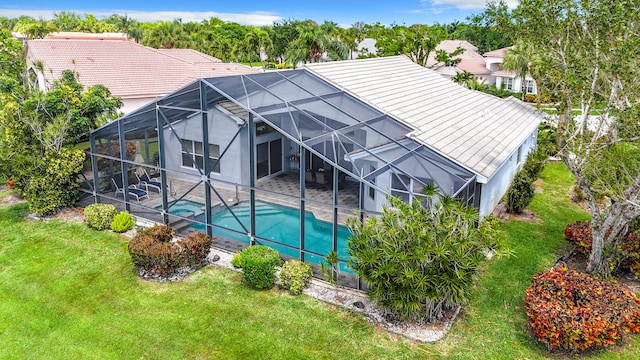 rear view of property featuring a patio, glass enclosure, and a lawn