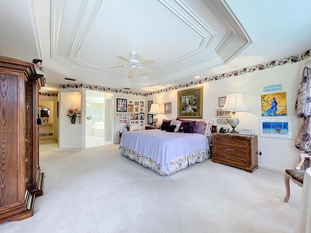 carpeted bedroom featuring ceiling fan, ornamental molding, connected bathroom, and a tray ceiling