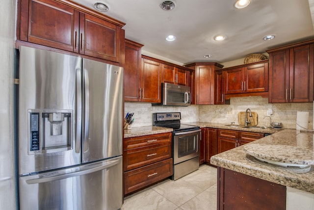 kitchen with light stone countertops, decorative backsplash, stainless steel appliances, sink, and light tile patterned floors