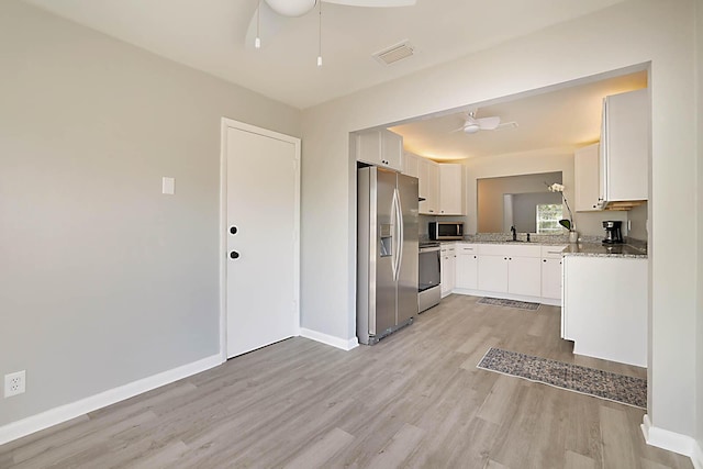 kitchen with stainless steel appliances, ceiling fan, white cabinets, and light stone counters