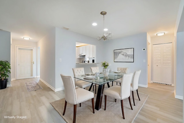 dining space featuring light hardwood / wood-style flooring and a chandelier