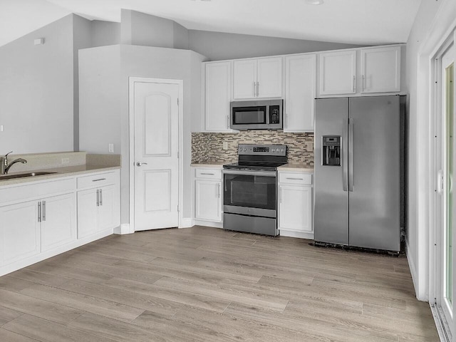 kitchen with white cabinetry, sink, lofted ceiling, decorative backsplash, and appliances with stainless steel finishes