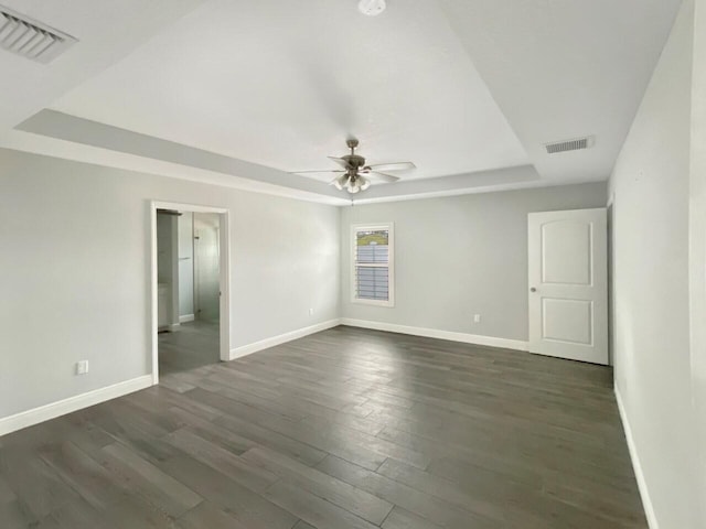 spare room with ceiling fan, dark hardwood / wood-style flooring, and a raised ceiling