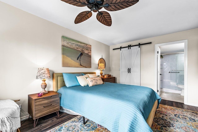 bedroom with dark wood-type flooring, a barn door, ceiling fan, and ensuite bathroom