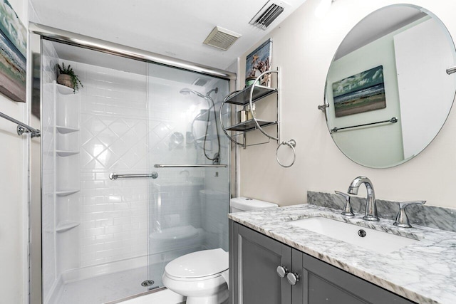 bathroom with toilet, vanity, and a shower with shower door