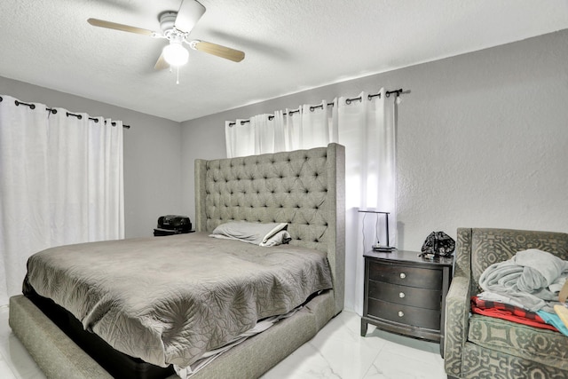 bedroom with ceiling fan and a textured ceiling