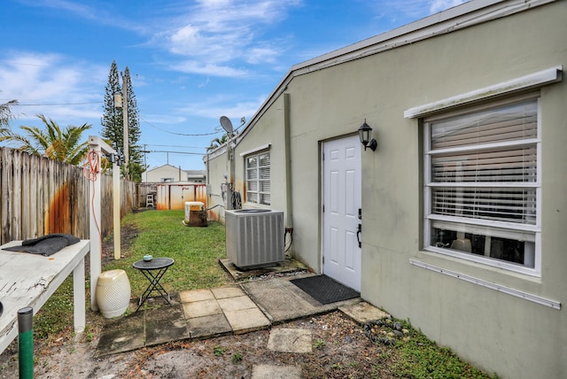 view of exterior entry with central air condition unit and a yard