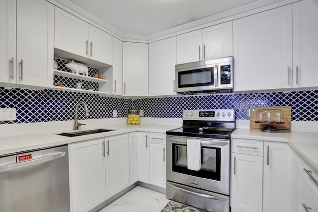 kitchen featuring decorative backsplash, appliances with stainless steel finishes, white cabinetry, and sink