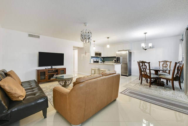 tiled living room with a textured ceiling and a notable chandelier