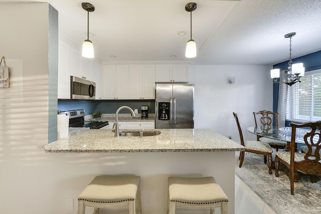 kitchen featuring white cabinetry, sink, a chandelier, a breakfast bar area, and appliances with stainless steel finishes