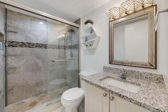 bathroom featuring vanity, toilet, and a shower with door