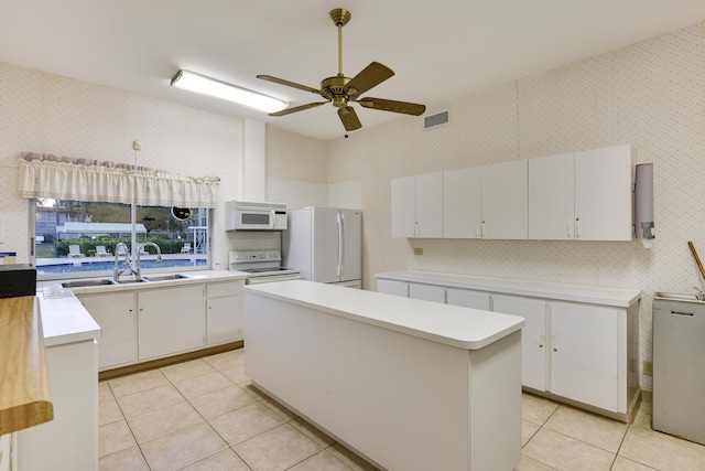 kitchen featuring a center island, white appliances, white cabinets, sink, and light tile patterned floors