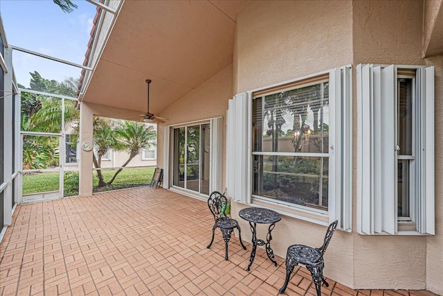 view of patio featuring ceiling fan and glass enclosure