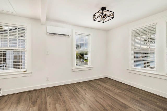 spare room with beam ceiling, plenty of natural light, hardwood / wood-style floors, and a wall mounted air conditioner