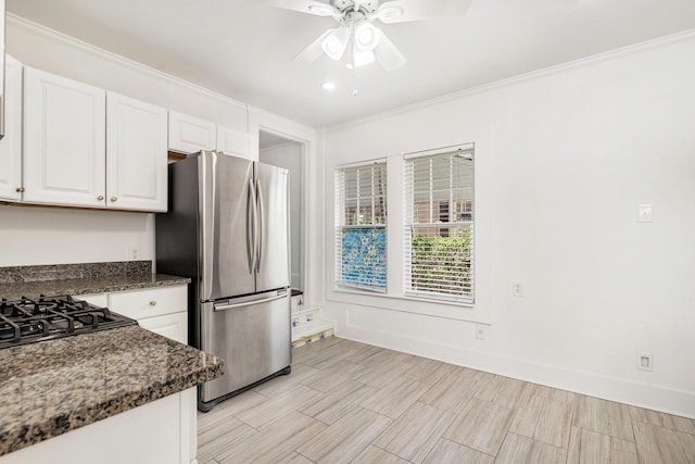 kitchen with stainless steel fridge, ornamental molding, dark stone counters, ceiling fan, and white cabinetry