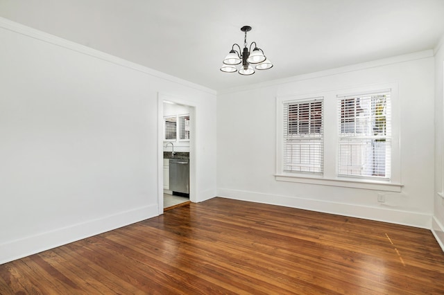 spare room featuring dark hardwood / wood-style floors, an inviting chandelier, crown molding, and sink