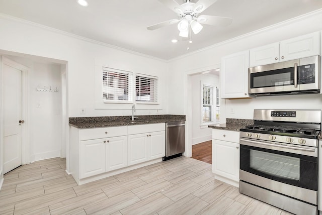 kitchen with white cabinets, ceiling fan, crown molding, and stainless steel appliances