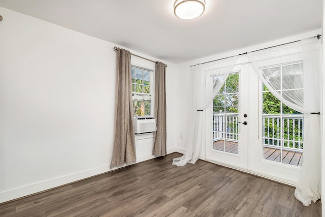 empty room with hardwood / wood-style floors, plenty of natural light, cooling unit, and french doors