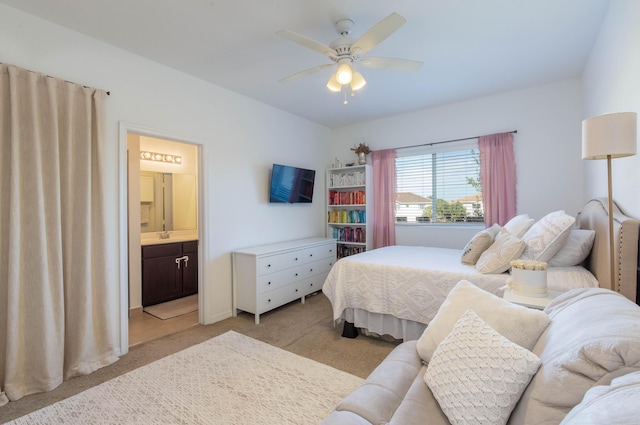 bedroom with light carpet, ensuite bath, and ceiling fan