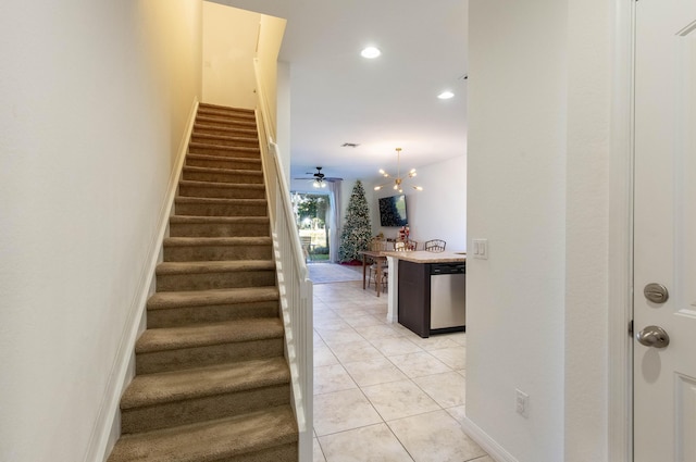 stairs with tile patterned flooring and ceiling fan with notable chandelier