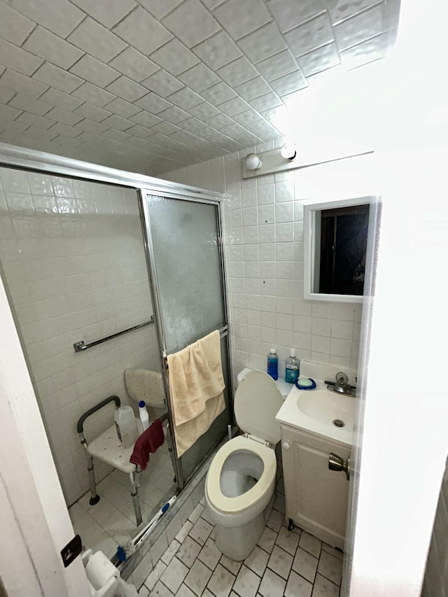 bathroom with sink, tile patterned flooring, toilet, tile walls, and walk in shower