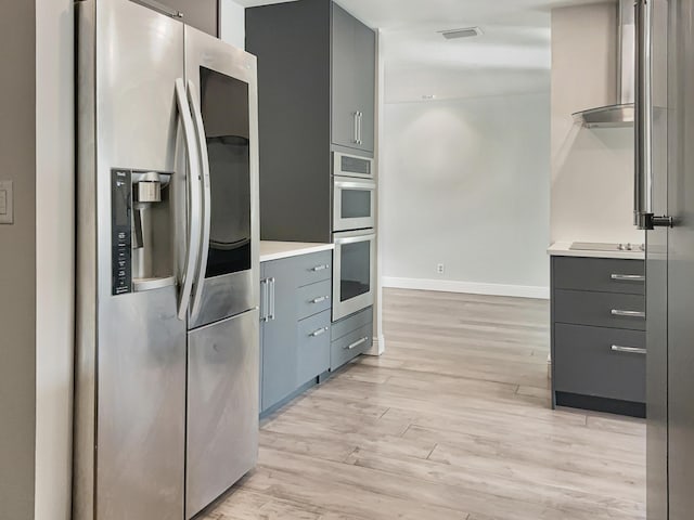 kitchen with appliances with stainless steel finishes and light hardwood / wood-style floors