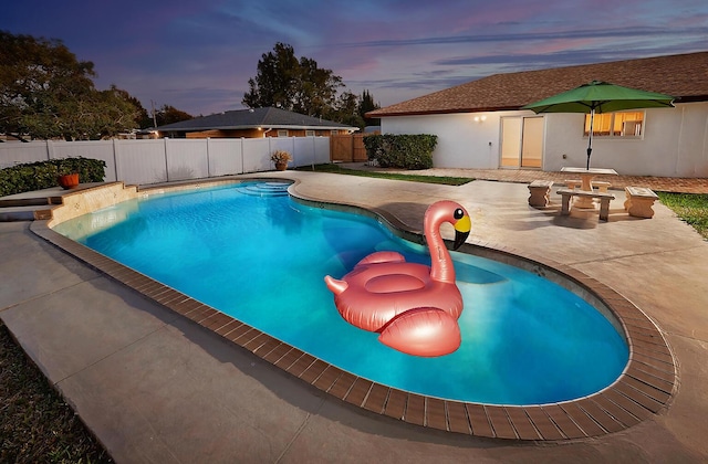 pool at dusk featuring a patio