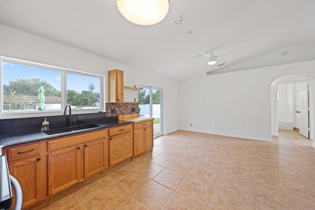 kitchen featuring tasteful backsplash, ceiling fan, sink, light tile patterned floors, and lofted ceiling