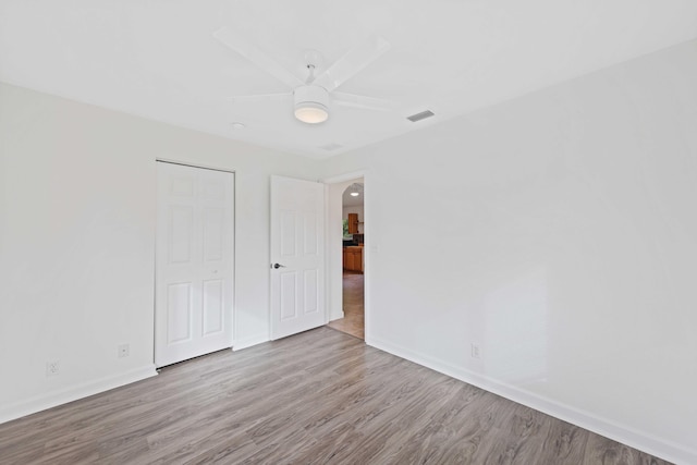 unfurnished bedroom featuring ceiling fan, light hardwood / wood-style flooring, and a closet