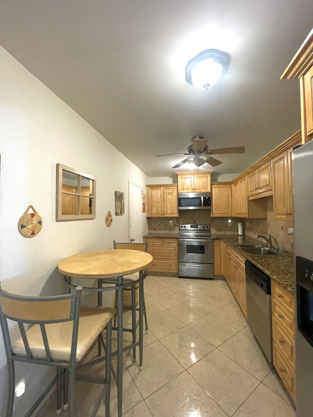 kitchen featuring dark stone counters, sink, ceiling fan, tasteful backsplash, and stainless steel appliances