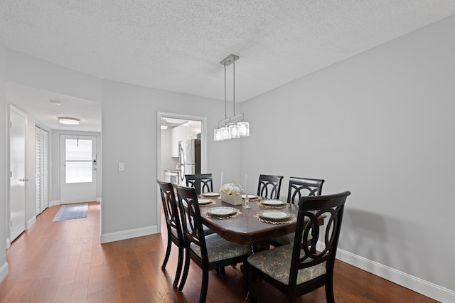 dining space featuring a textured ceiling and dark wood-type flooring