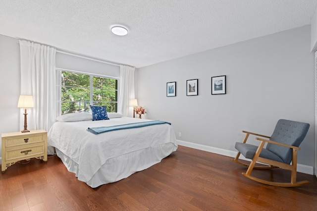 bedroom featuring a textured ceiling and dark hardwood / wood-style floors