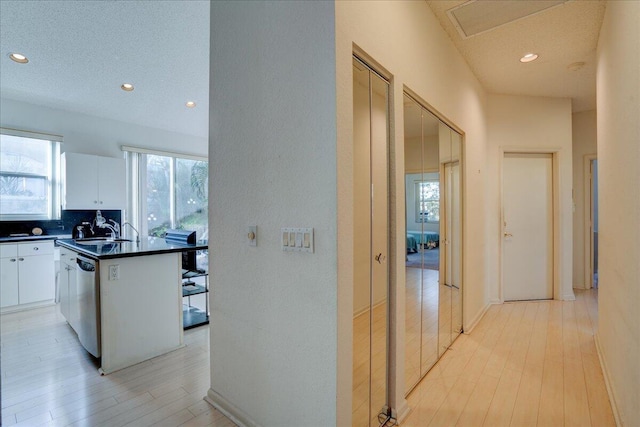 hallway with a textured ceiling, light wood-type flooring, and sink