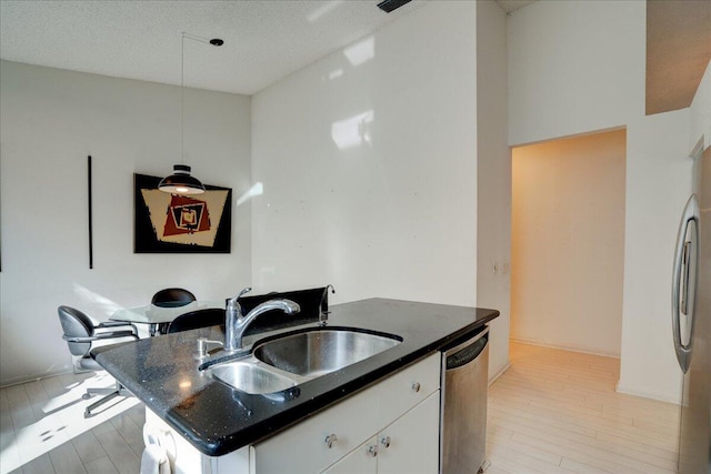 kitchen with appliances with stainless steel finishes, sink, a center island with sink, white cabinets, and hanging light fixtures