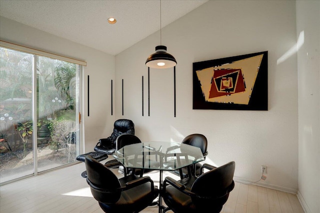 dining space featuring a textured ceiling, light hardwood / wood-style flooring, and lofted ceiling