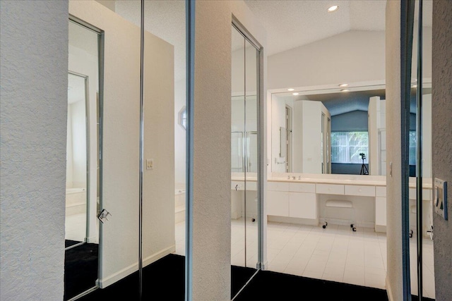 corridor with a textured ceiling, sink, and vaulted ceiling