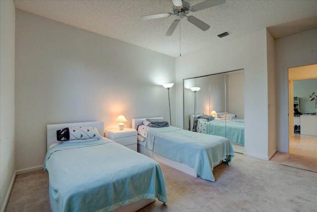 bedroom with ceiling fan, light colored carpet, a textured ceiling, and a closet