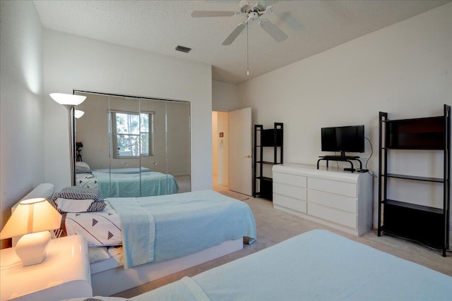 carpeted bedroom with a textured ceiling, a closet, and ceiling fan