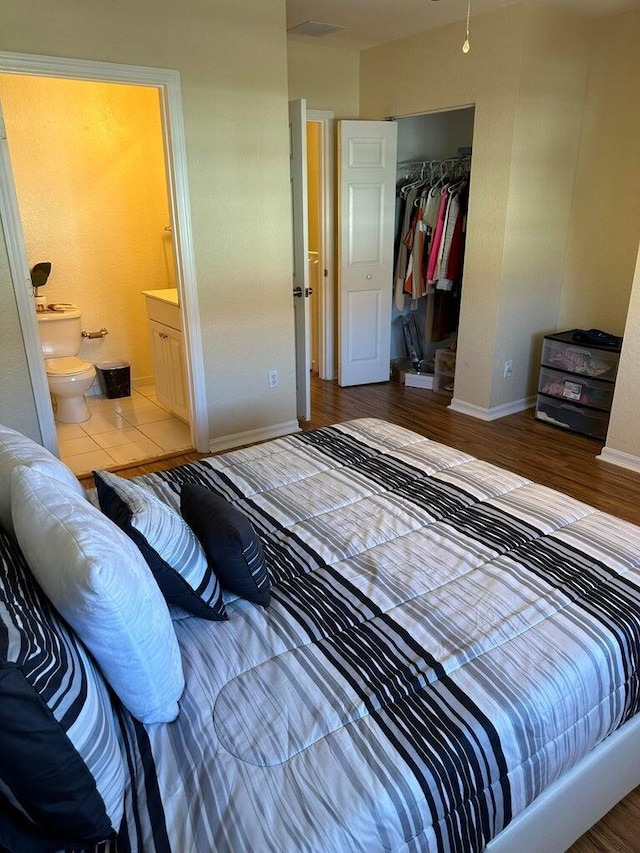 bedroom with a closet, wood-type flooring, and ensuite bath