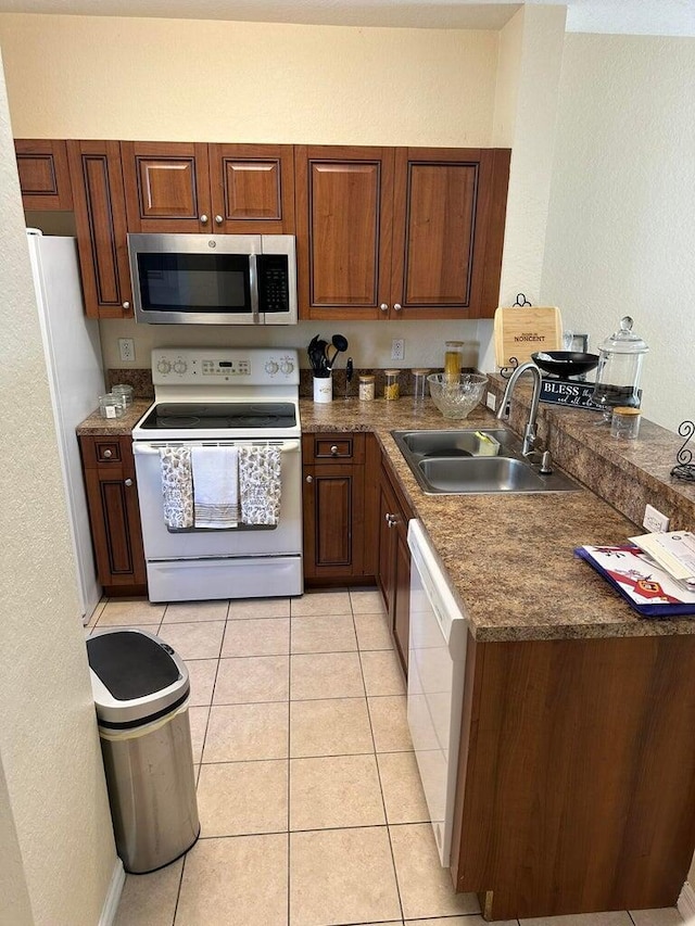 kitchen with light tile patterned floors, white appliances, and sink