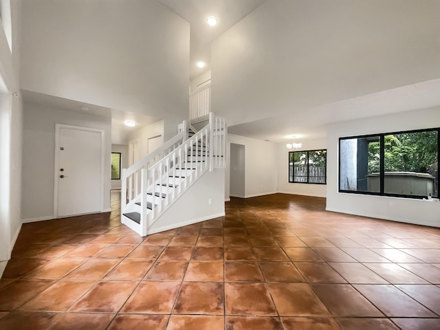 unfurnished living room with tile patterned floors, a high ceiling, and a chandelier